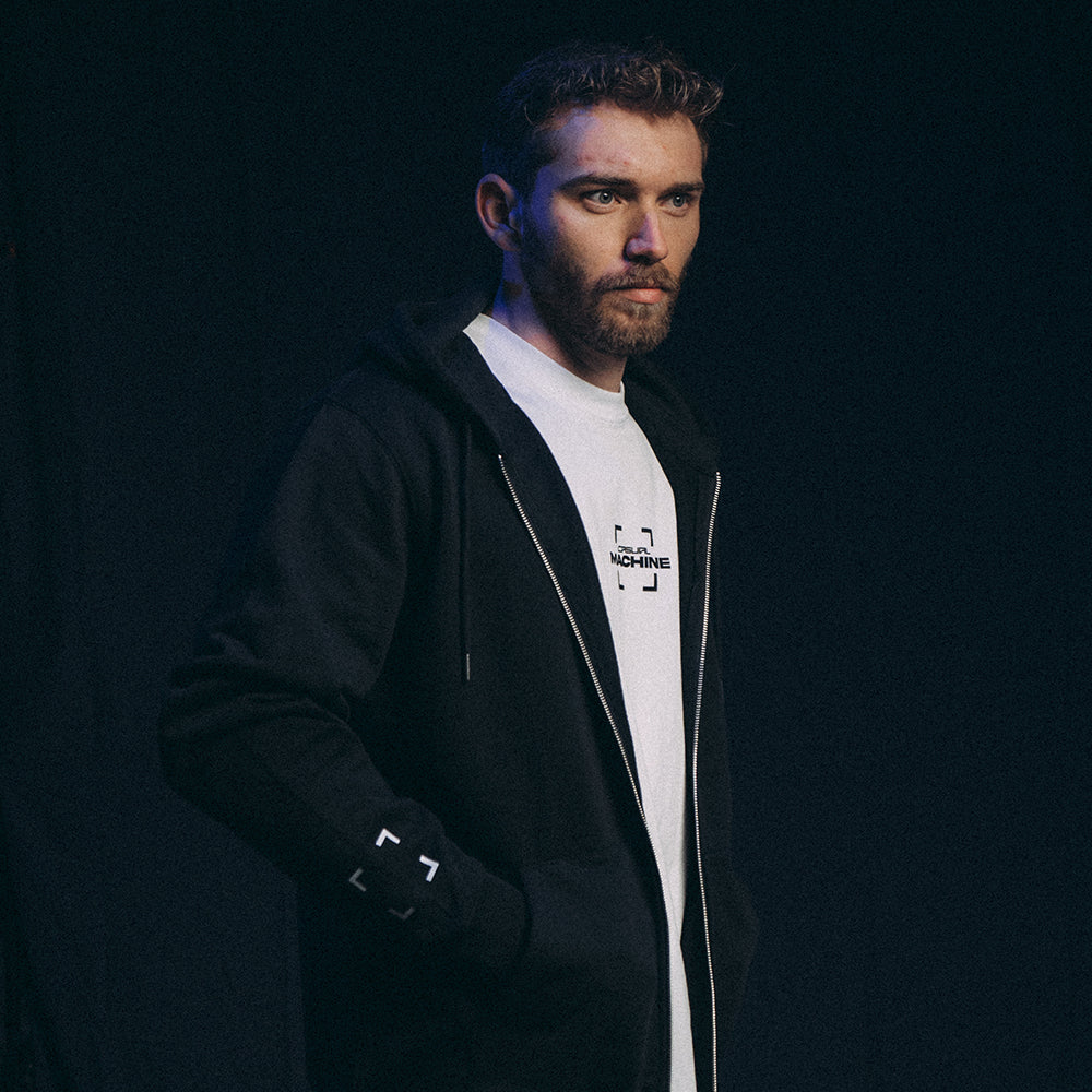 Mannequin homme de profil portant le Hoodie Basics 2.0 noir zippé en coton biologique et polyester recyclé, avec sérigraphie côté cœur, visible sur le T-shirt Basics 2.0 blanc en dessous