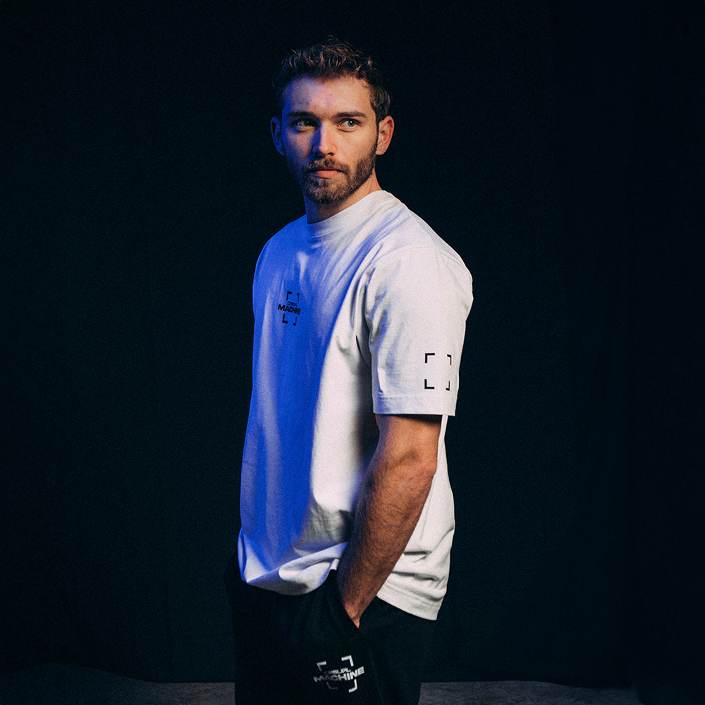 Vue de profil du mannequin homme portant le T-shirt blanc Basics 2.0, coupe oversize et design minimaliste, sérigraphie côté cœur