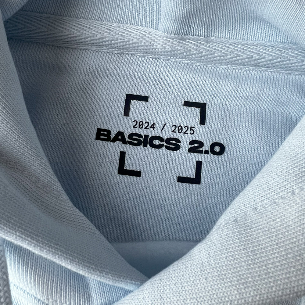 Détail du hoodie Basics 2.0, mettant en avant le transfert au col, couleur bleu clair, coupe oversize