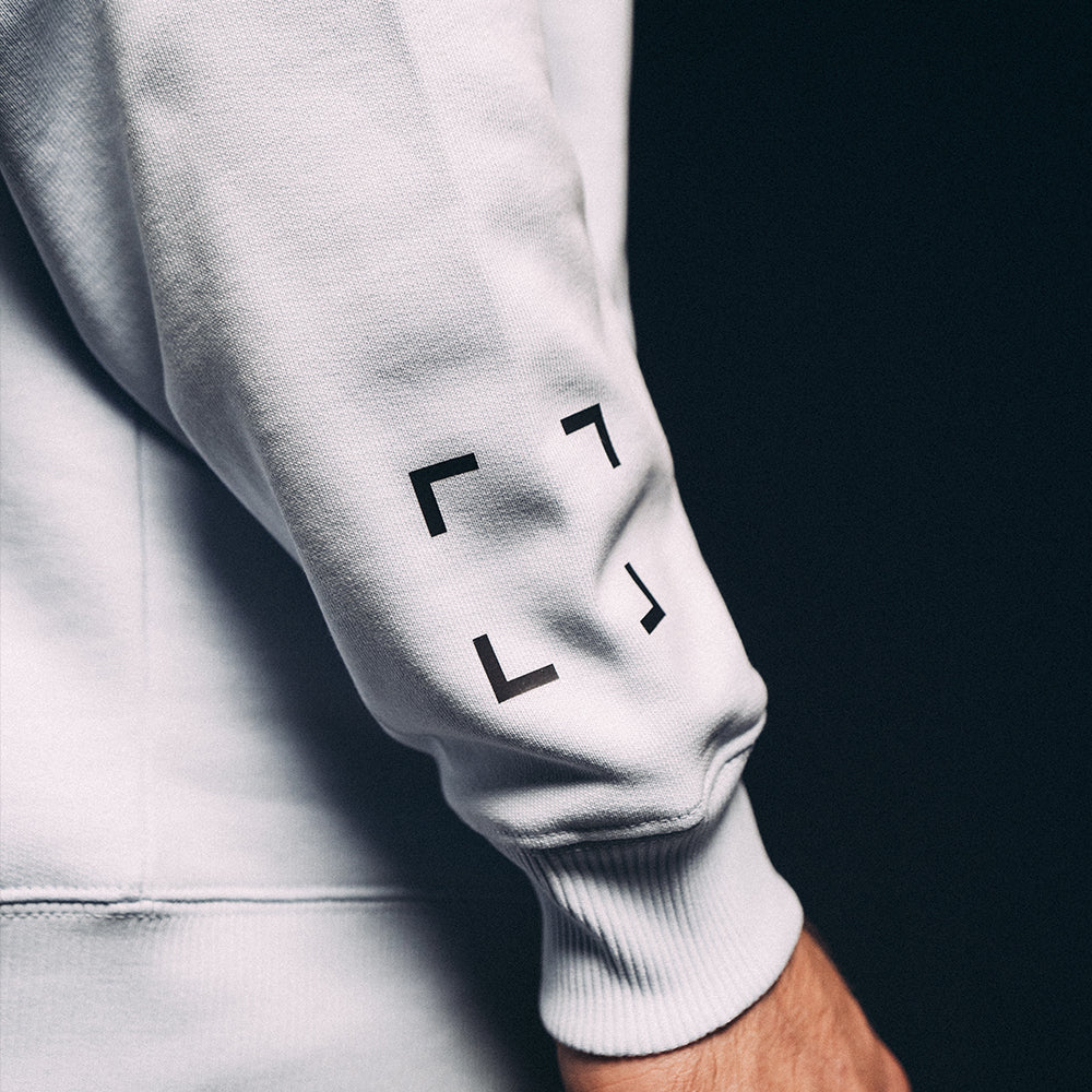 Détail des manches du hoodie Basics 2.0, transfert sur le bras gauche, coupe oversize