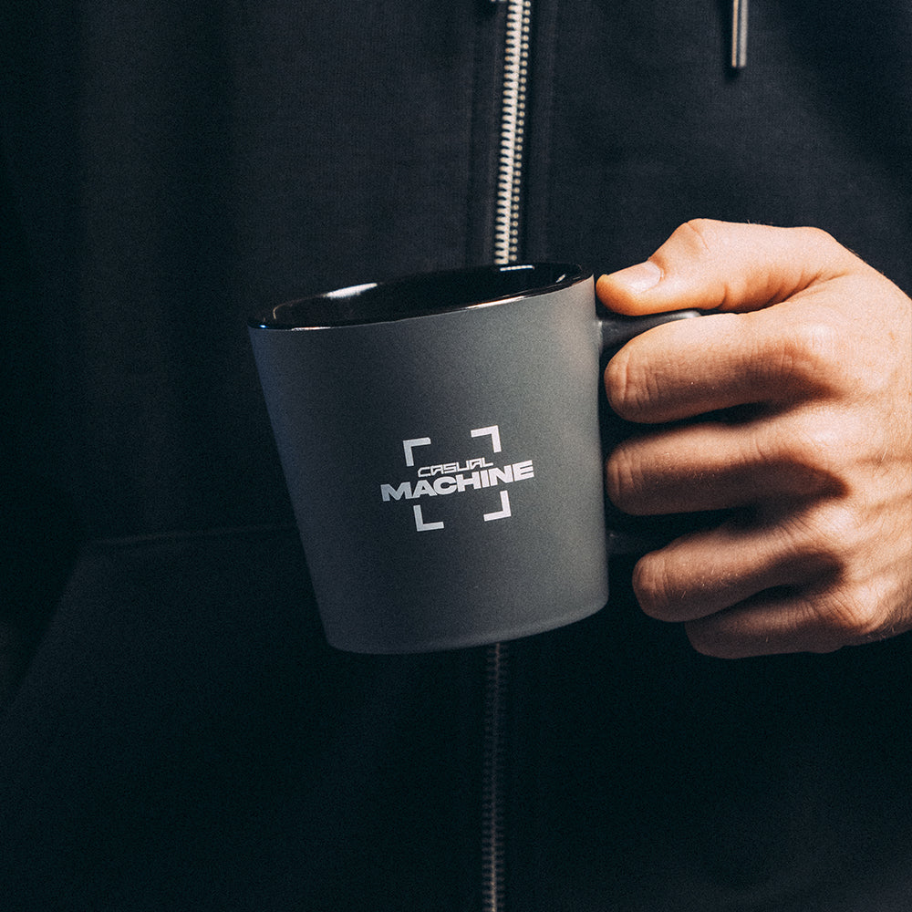 Mug gris 370 ml en céramique finition mate, sérigraphie logo, lavable au lave-vaisselle, gros plan sur une main tenant le mug
