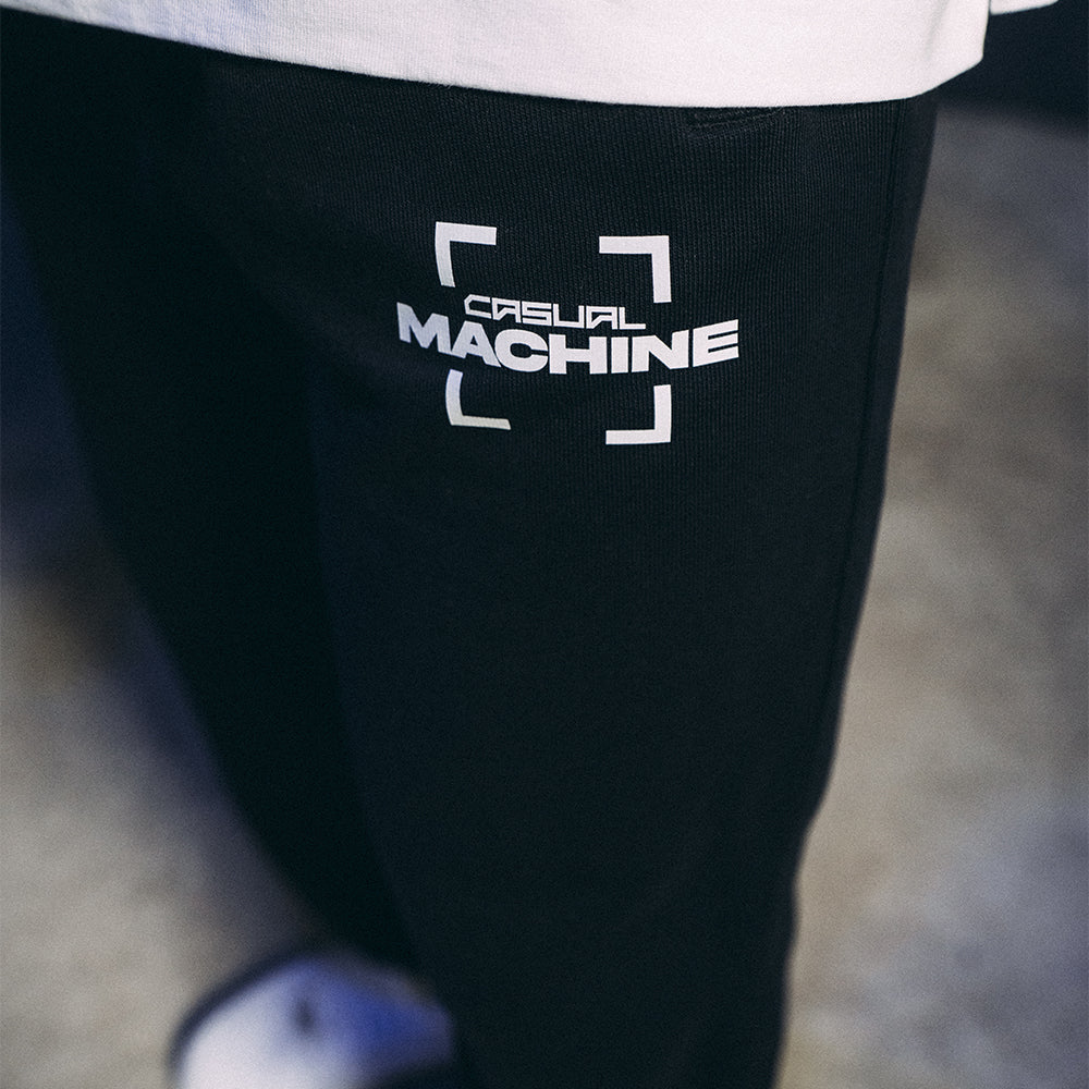 Détail du logo sérigraphié sur la jambe gauche du Jogging Basics 2.0, design sobre et élégant